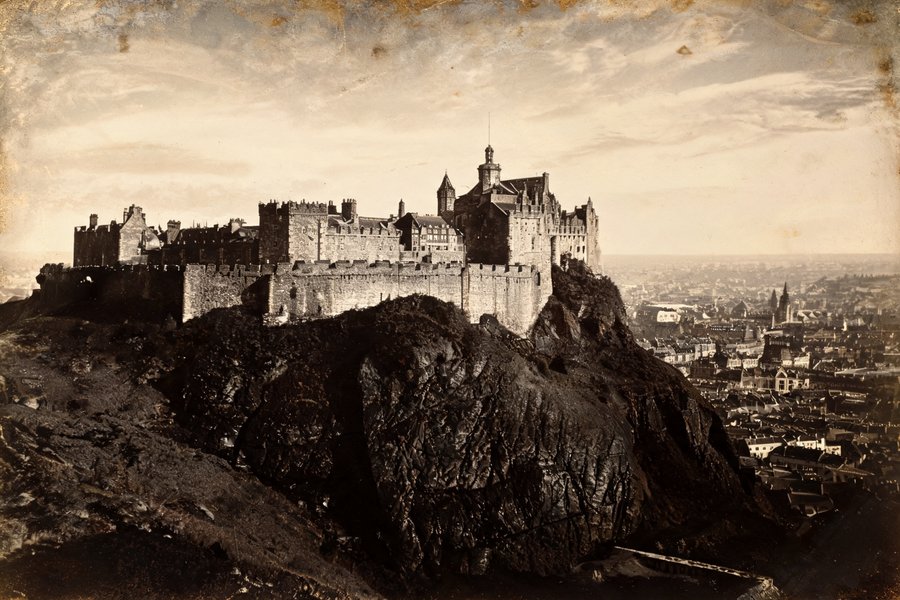 Il Castello di Edimburgo sulla roccia vulcanica nera: le mura medievali e i bastioni si stagliano sul cielo dorato in dagherrotipo